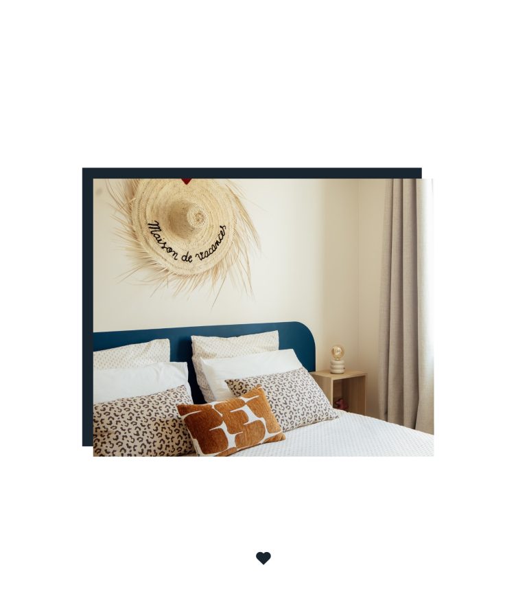 Lit double avec tête de lit bleue, coussins léopard et terracotta, sous un chapeau mural « Maison de vacances ».