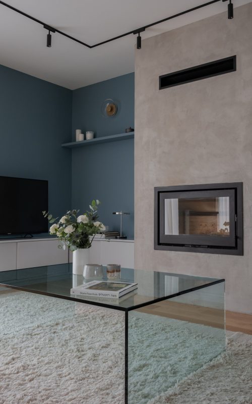 Cheminée centrale avec finition enduit minéral intégrée à un mobilier sur mesure dans une pièce de vie aux murs bleu profond